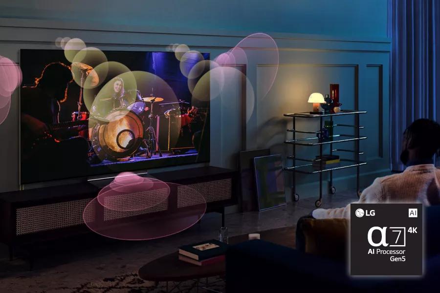 A couple watches a concert on TV with sound waves reverberating from the TV. Alpha7 4K Gen5 AI Processor chip. 