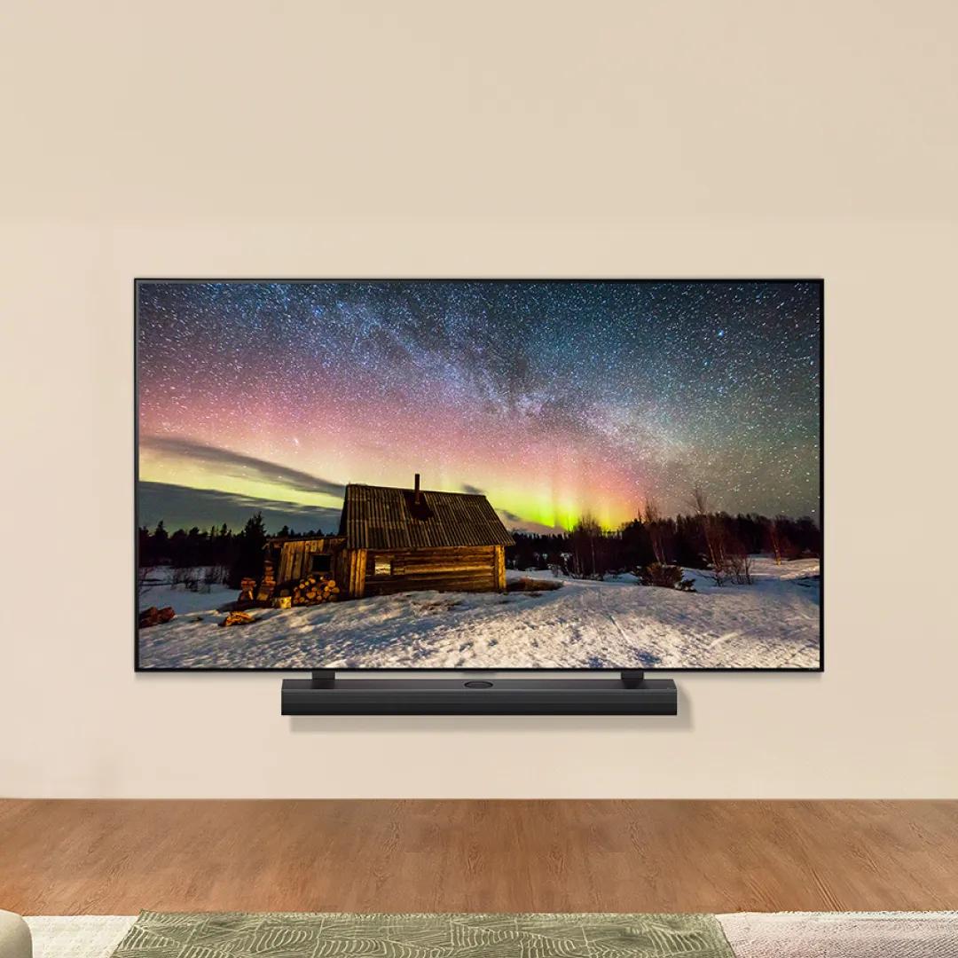 An LG TV in a living room setting displays a vivid picture of the Northern lights. A soundbar sits beneath the TV. 