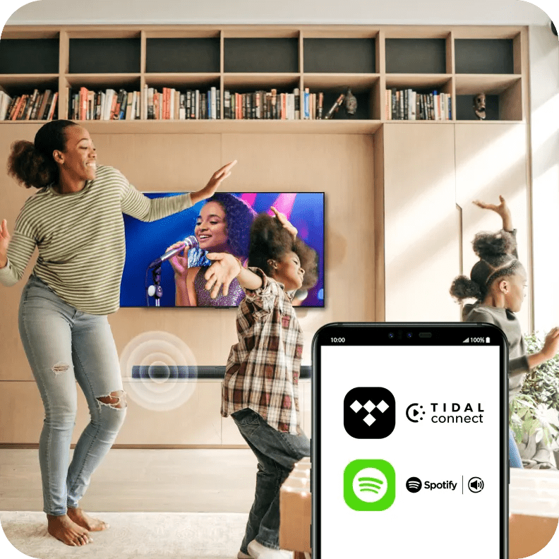 Mom and kids dance to music on TV, streaming from TIDAL and Spotify apps shown on a smartphone.
