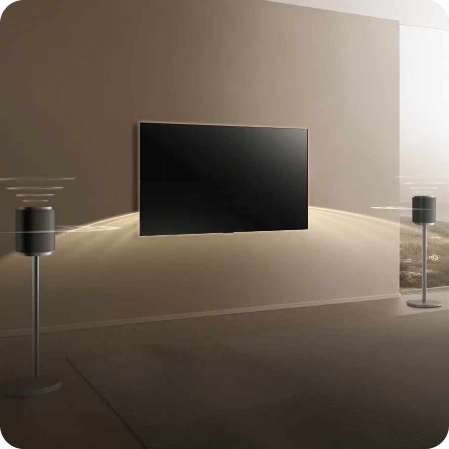 Living room scene with a wall-mounted LG TV and two standing Sound Suite speakers emitting sound waves on either side, illustrating a direct wireless audio connection setup.