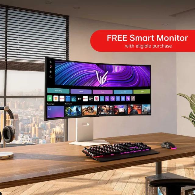 A widescreen monitor on a desk within an office. “Free smart monitor with eligible purchase” text above.