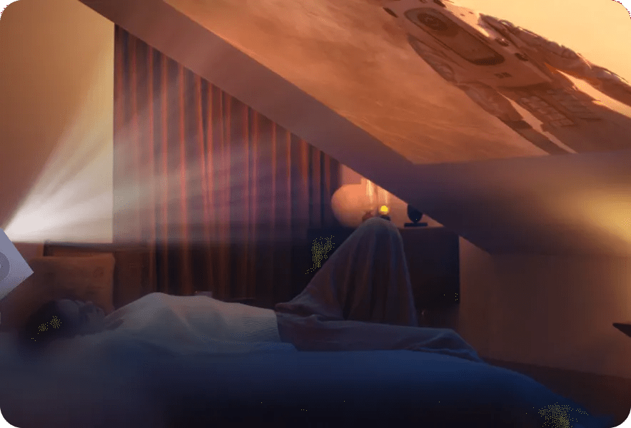 A person relaxes in bed while an LG CineBeam projector casts a sharp image of an astronaut onto a slanted ceiling.