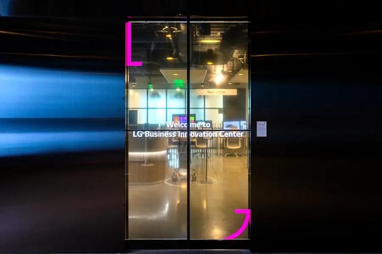 The glass sliding doors leading from the entryway to the main space of the LG LA Business Innovation Center. Transparent OLED transforms them from ordinary doors to a unique signage opportunity, displaying a stylized LG motif and the words Welcome to LG Business Innovation Center.
