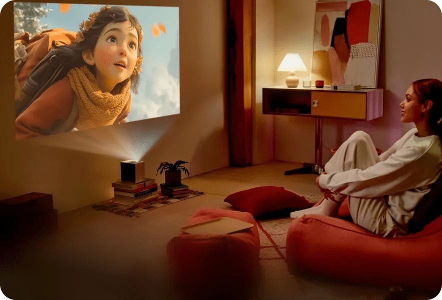 A young woman sits comfortably on the floor in a cozy living room, smiling as an LG CineBeam S projects a colorful animated film scene of a girl with a backpack against a bright sky.