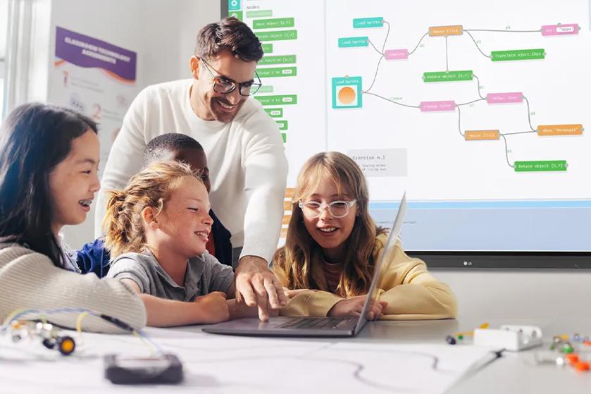 A smiling teacher helps his students with an LG gram laptop. Behind them, an LG CreateBoard displays educational information.