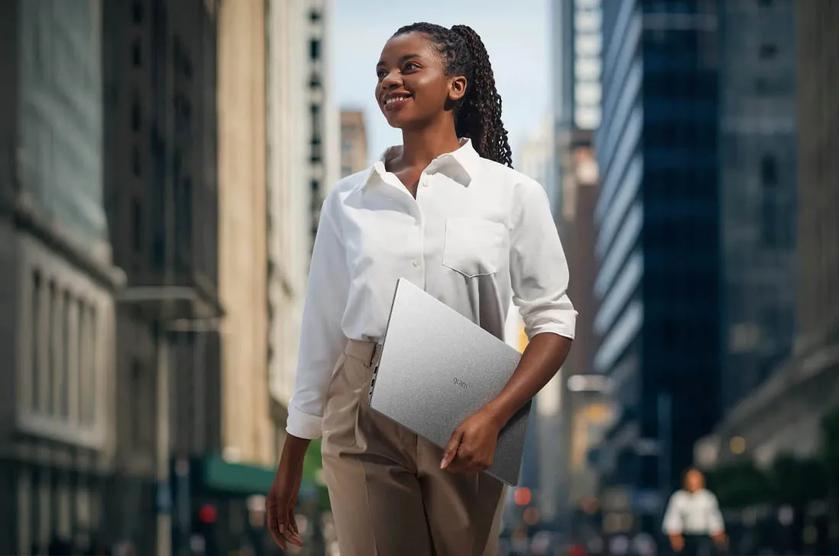 A business woman walks through the city holding 16Z90U-K gram laptop