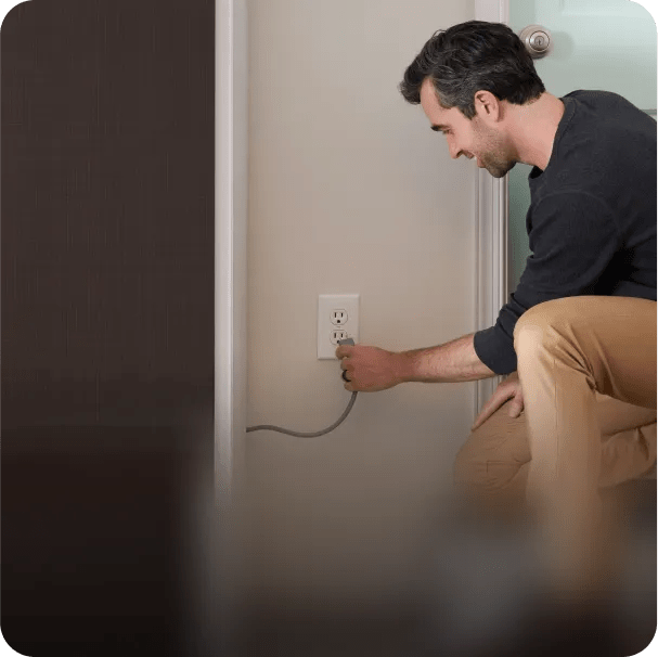 A man plugs in his LG Styler® to a standard home outlet.