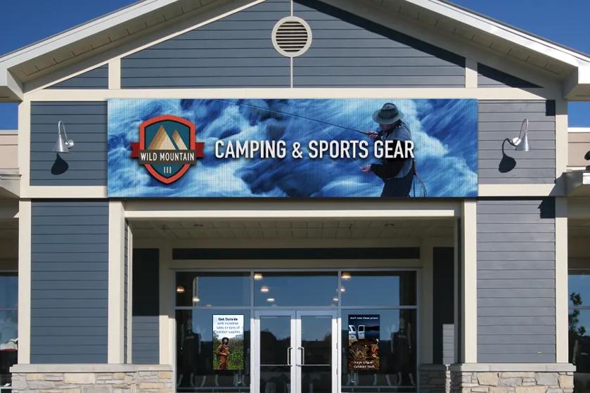 An exterior of a camping and sports gear store with LG digital signage showcasing the store name and logo.