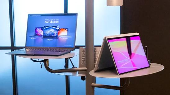 Two LG laptops on a circular stand in the LG LA Business Innovation Center's gram lounge area.