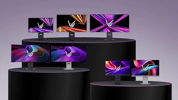 A lineup of LG UltraGear monitors in different sizes and designs displayed on tiered black podiums, each screen showing vivid abstract graphics in purple, orange, and pink tones.