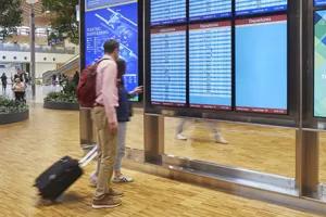 A passenger stands in front of an LG signage display, checking his flight information.