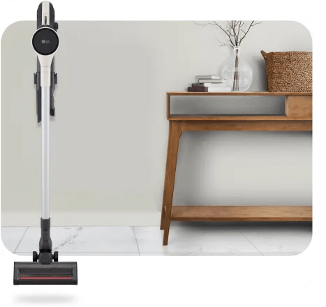 A front-facing LG stick vacuum is mounted to the wall in a modern living room.