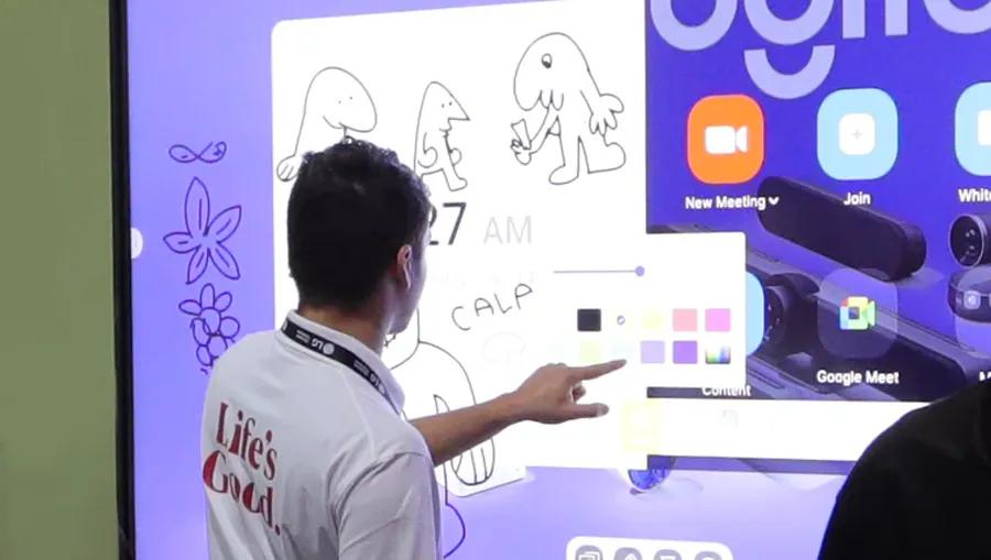 A man faces away from the camera, using his finger to draw and write on an LG CreateBoard in the LA Business Innovation Center.