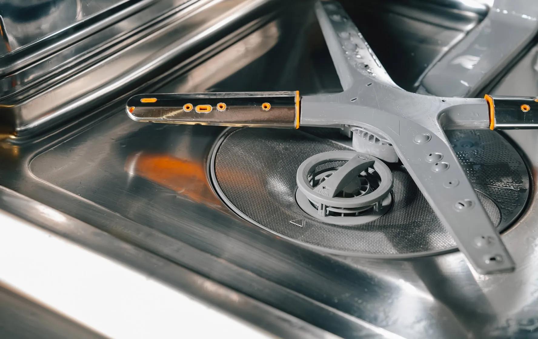 The interior floor of an LG dishwasher is covered in food debris and hard water stains. - After