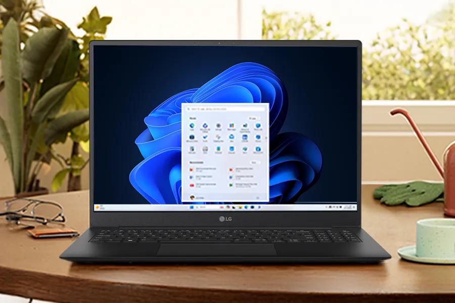 LG laptop on a wooden desk displaying a Windows menu with a blue abstract background.