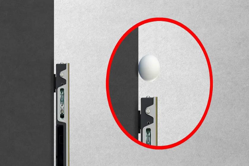 Close-up of a black and white wall with a metallic fixture at the edge and a white sphere highlighted by a red circle.