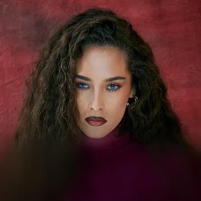 Photo of Maeta against a dark red background.