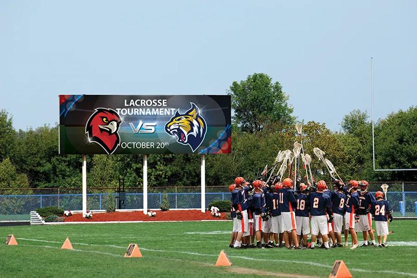 A school field with lacrosse players and an LG outdoor DVLED display.
