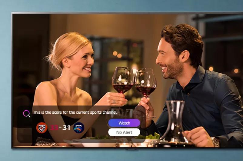 A man and a woman clinking glasses on a TV screen while sports alerts being notified