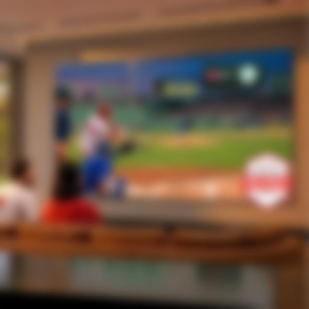 A man and woman watching a baseball game on a big screen TV.