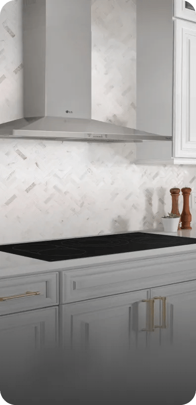 An LG hood sits flush with the cabinetry above an LG cooktop in a bright, modern kitchen.