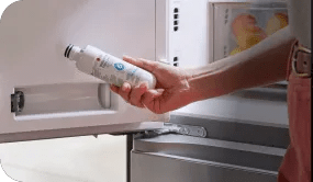 A hand showing how easily replacing a water filter in an LG refrigerator door.