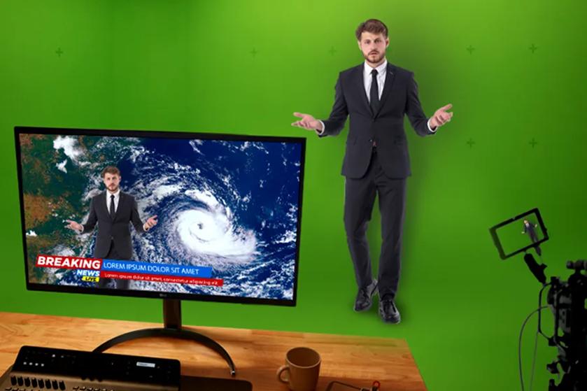 A weatherman stands in front of a green screen while the camera rolls. On a desk is an LG Monitor showing the anchor and the weather map being overlaid on the green screen.