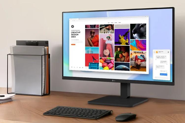 A smooth wooden desk with an LG Full HD montor on it. Its display shows a bright wallpaper, with a window open. Text in the window reads Creative Design Ideas, and the rest of the window is filled with small bright photographs of people, food, and art. Beside the monitor is a mouse, keyboard, and notebooks in a file holder.