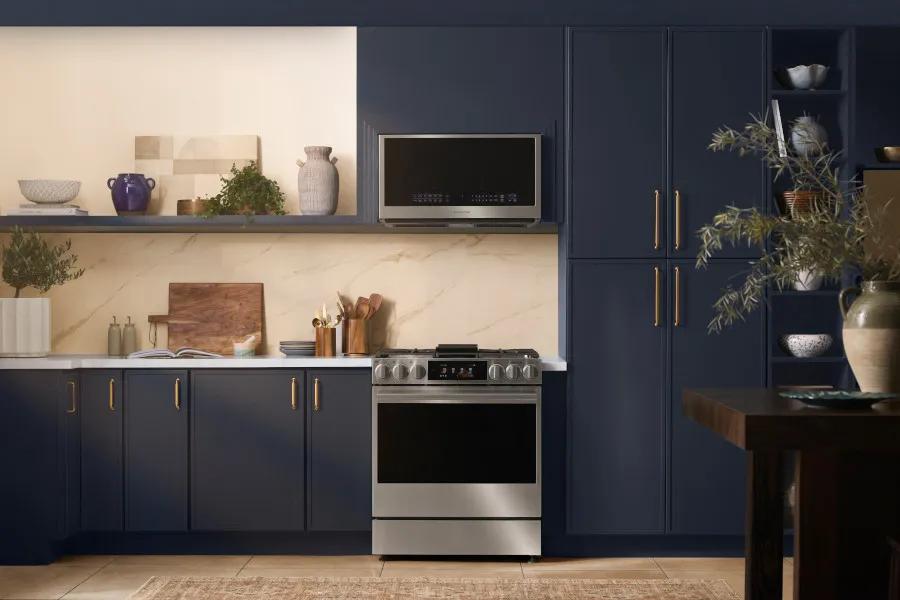 MHEU1738X over-the-range microwave installed in elegant navy blue kitchen with stainless steel range and marble backsplash