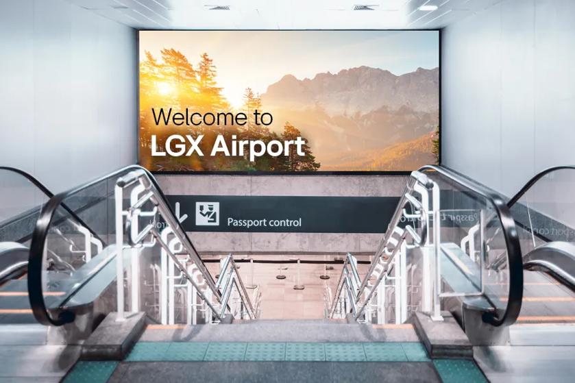 Escalator in airport terminal with large LG signage welcoming visitors to the airport.