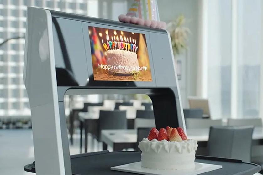 CLOi carries a cake, with a Happy Birthday graphic on her display.