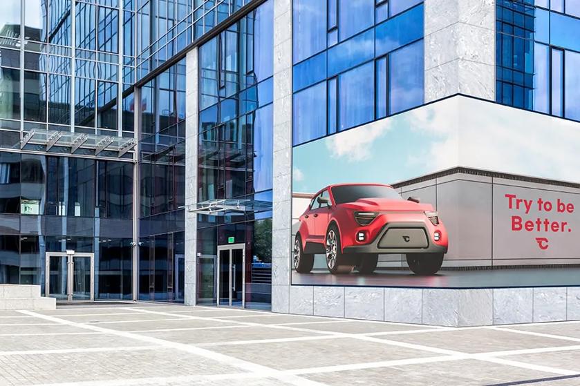 A modern building with a glass facade and a large corner billboard displaying a red SUV and advertisement text.
