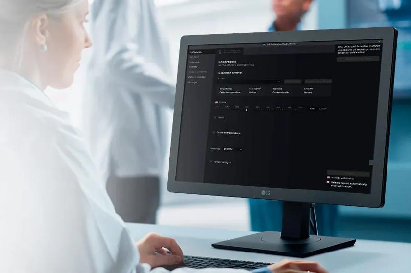 Person using an LG monitor displaying a calibration interface in a professional setting.