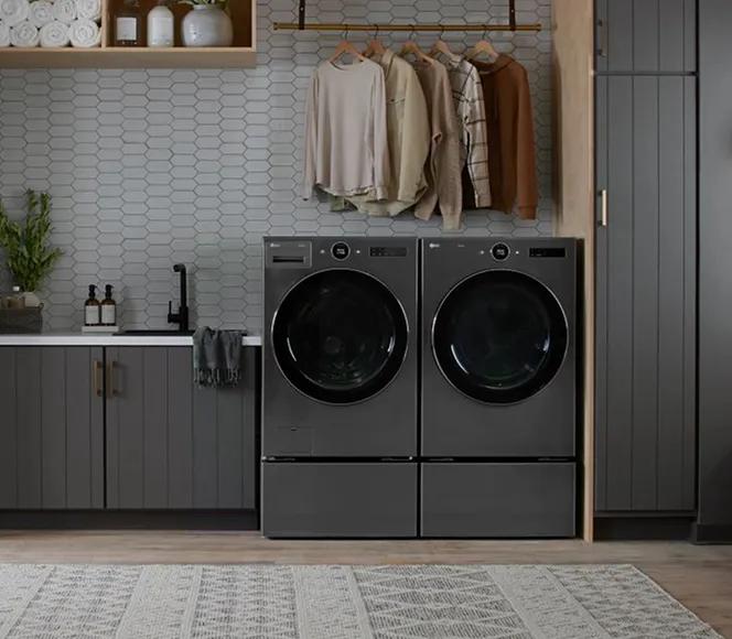 Dark gray front-load washer and dryer in a laundry room with dark gray cabinets.