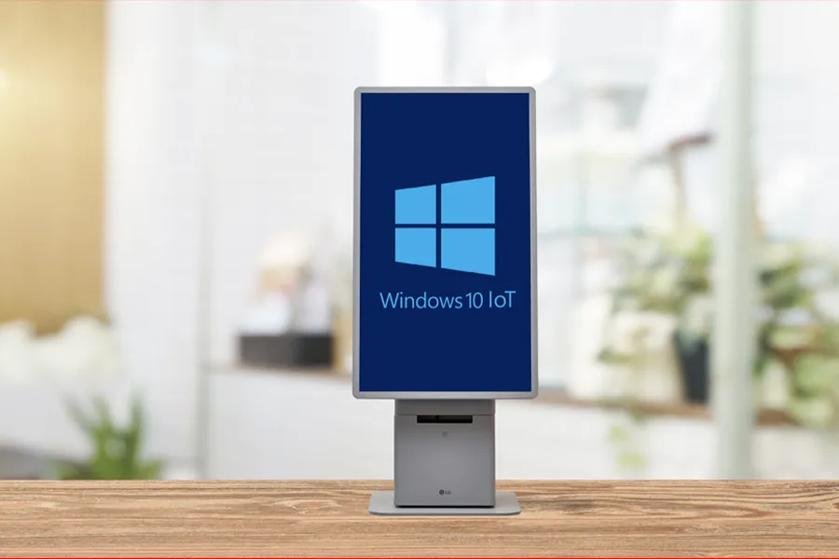 Digital kiosk displaying the Windows 10 IoT logo on a wooden surface in an indoor setting.