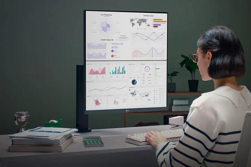 Person working on a computer with a large monitor displaying charts and graphs.