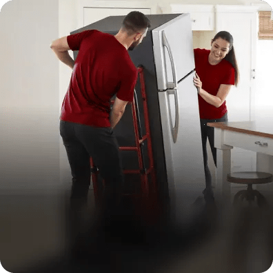 LG installation pros haul away a refrigerator on a hand truck.
