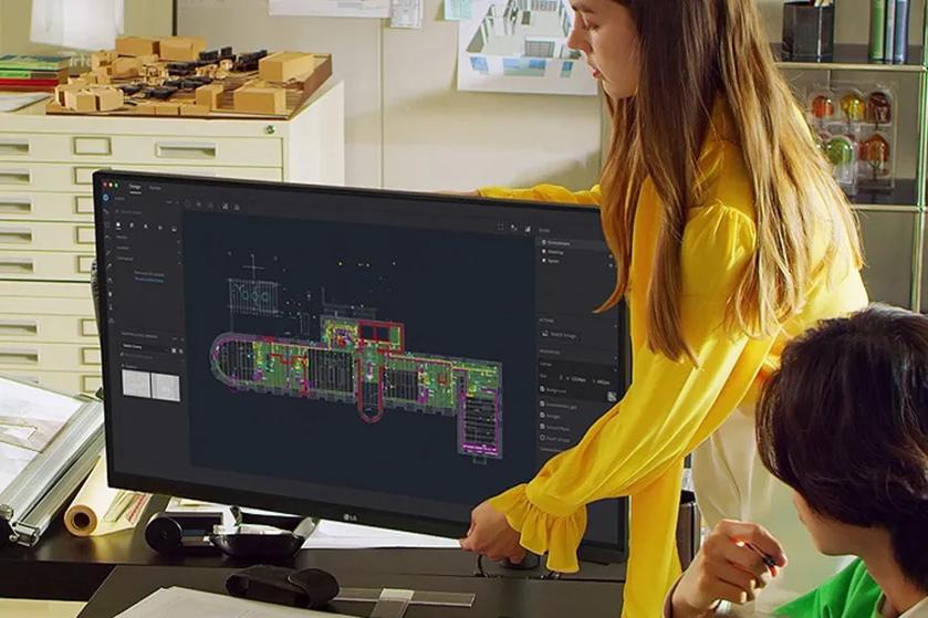 Two people discussing a technical design displayed on a computer monitor in an office setting.