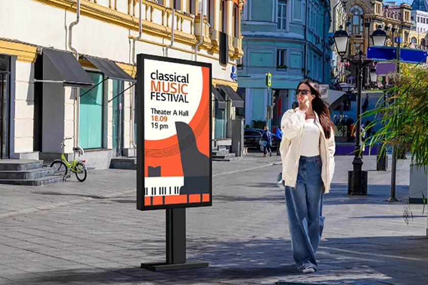 A woman walks past a digital billboard advertising a Classical Music Festival on a city street with historic architecture.