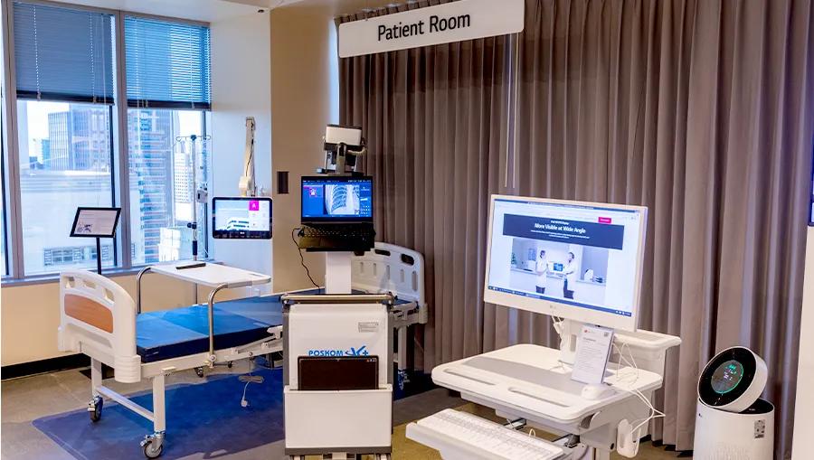 Patient room zone in the LG LA Business Innovation Center, with transportable All-in-One Cloud Device on a rolling cart and medical monitors around a patient bed.