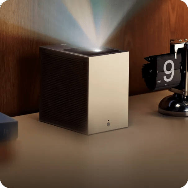 An LG CineBeam S projector sits on a table, projecting bright light upward, next to a retro flip clock.