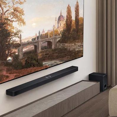 LG Soundbar and TV system mounted on a living room wall, an outdoor scene of a medieval bridge and tower is shown on the screen.