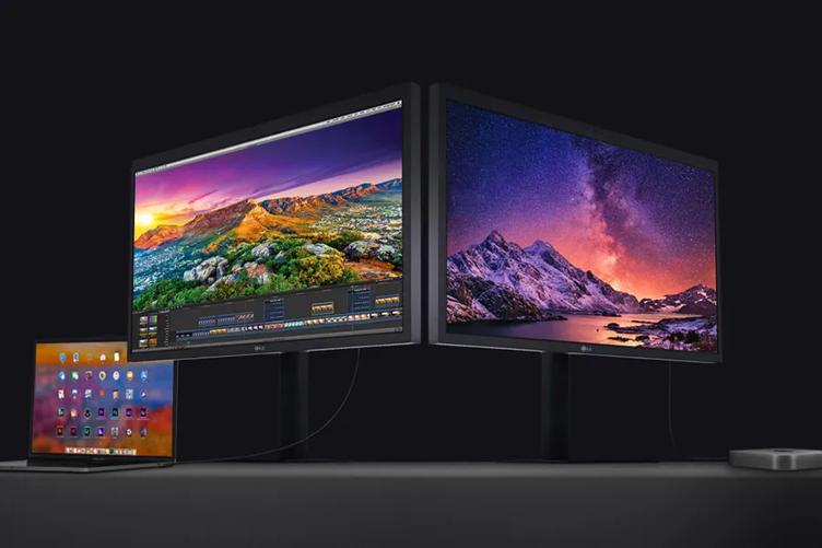 Two large monitors displaying vivid landscapes with a laptop showing application icons on a dark surface.