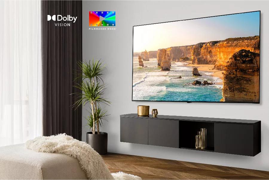 A TV in a stylish living room plays nature scene on-screen. Dolby Vision logo. FILMMAKER MODE logo.