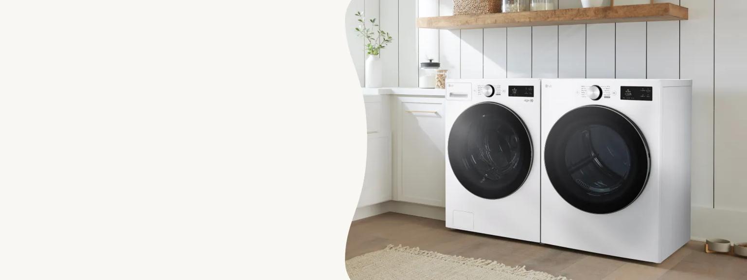 A bright, modern laundry room features a white LG front load washing machine and matching dryer situated beneath a floating wooden shelf and shiplap walls with white cabinetry. 