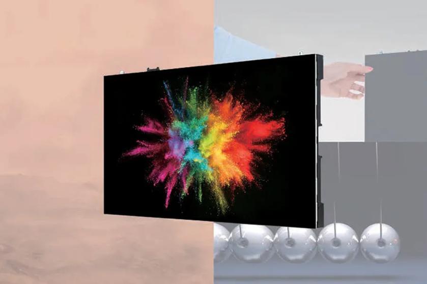 A screen displays a vibrant burst of colors against a split background of peach and grey, with metallic spheres below.