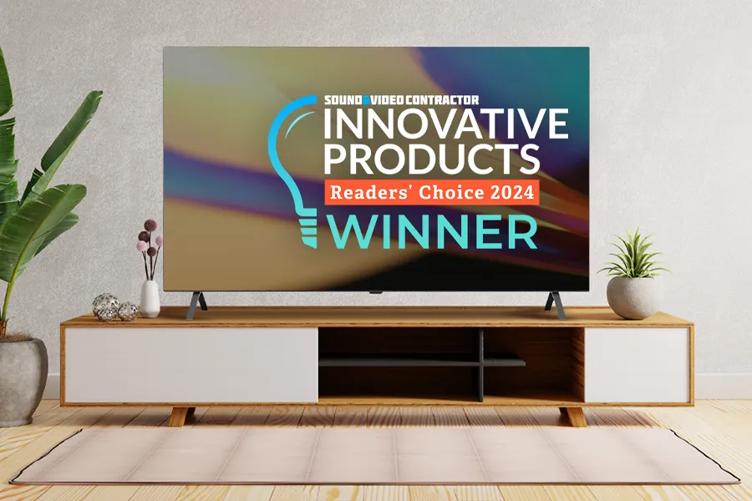 A modern space that could be a chic hotel room or lobby, with some decorative plants and an LG OLED TV on a low stand. An abstract colorful background is on the TV, with an award graphic overlaid on it. The graphic says: Sound & Video Contractor Innovative Products Readers Choice 2024 Winner.