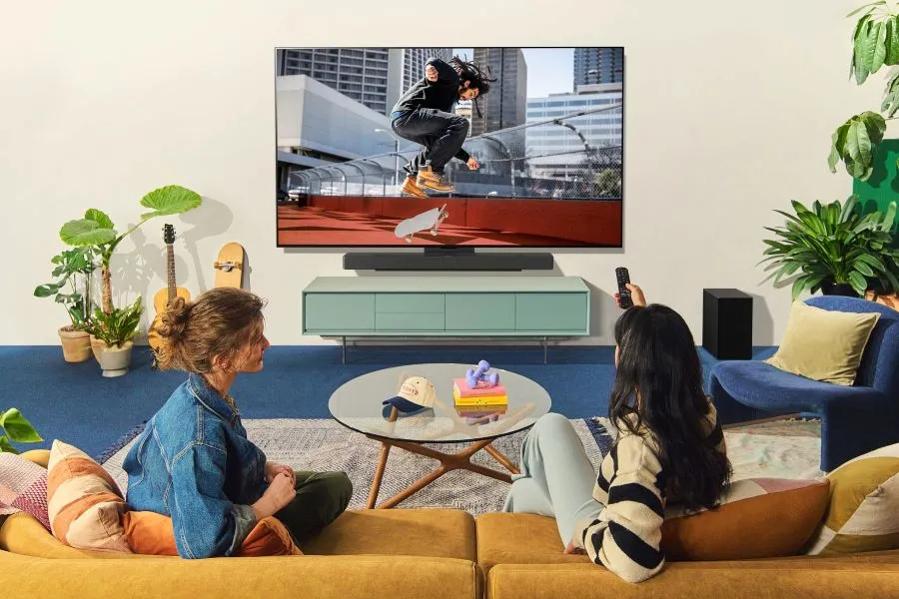 Two people watching skateboarder on smart TV