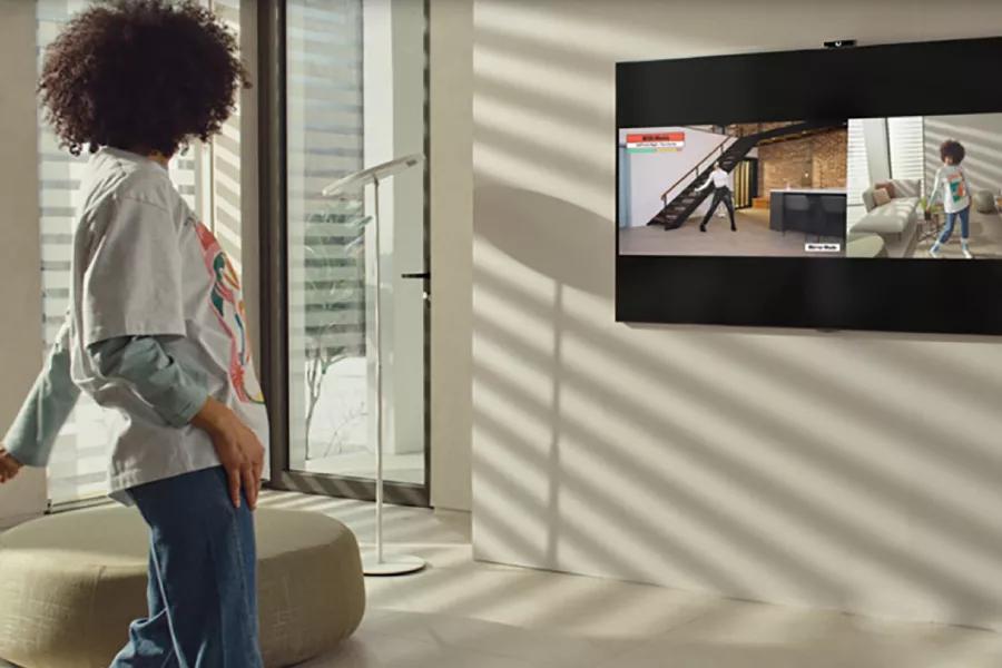 A woman strikes a pose in front of her TV while the Smart Cam shows her on-screen.