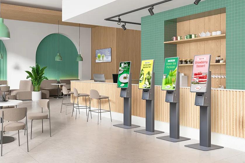 Interior of a modern cafe with digital kiosks and a seating area.